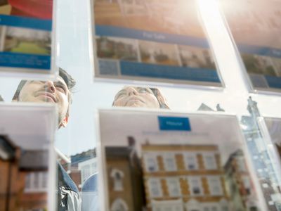 Two people look through a window at real estate advertisements