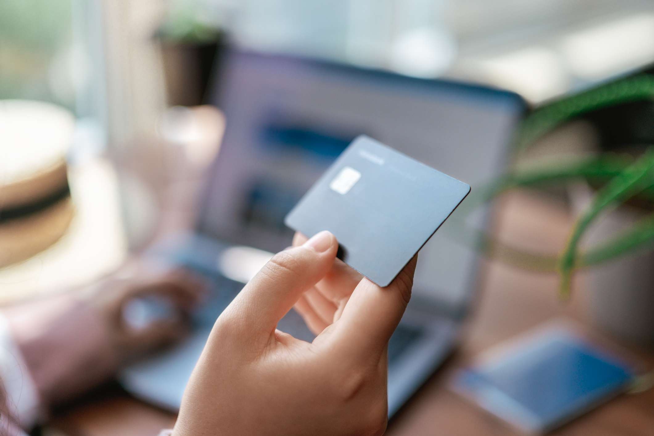 A person uses a credit card to buy something online. Credit card in hand close up