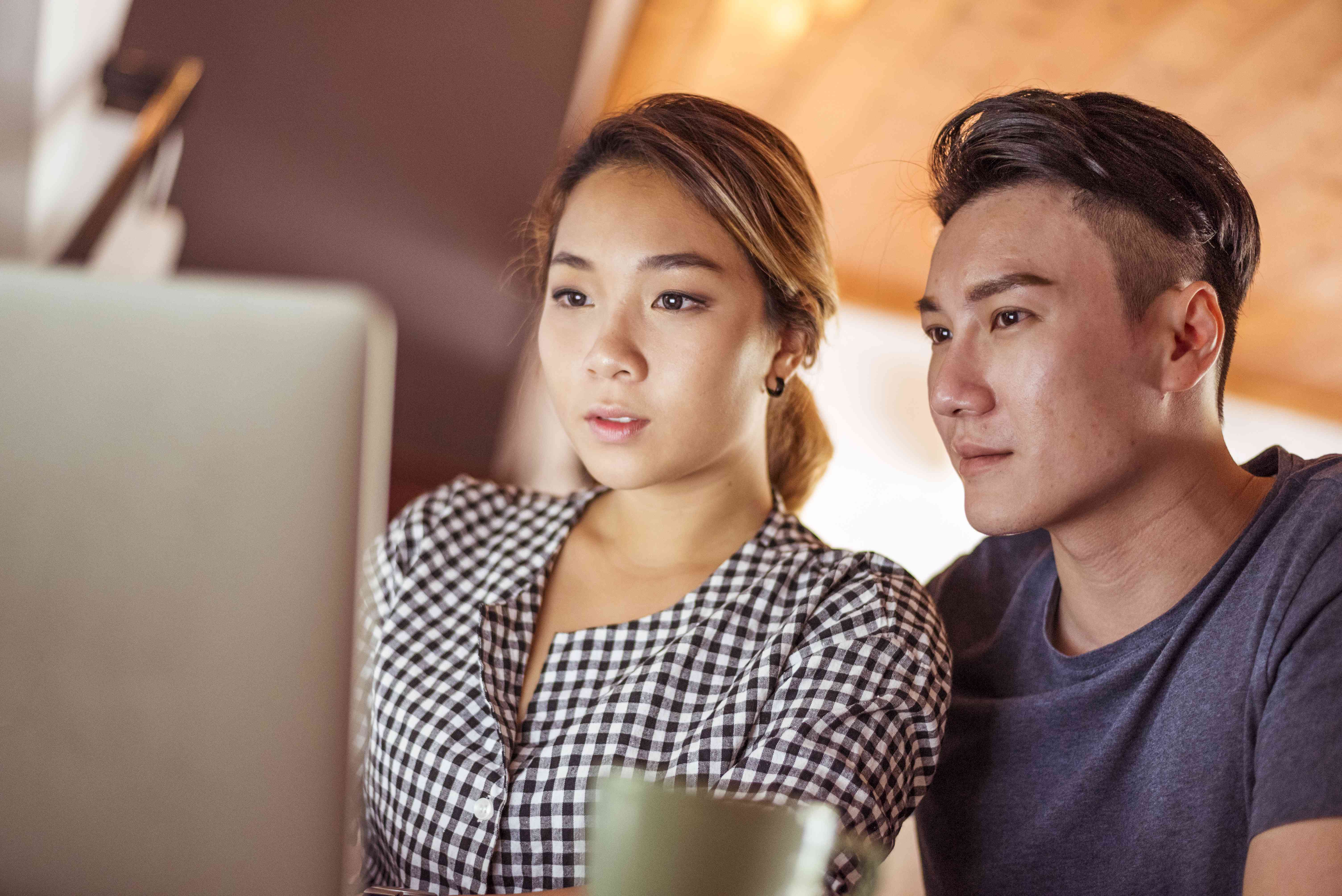 Young Asian couple studying laptop together at home