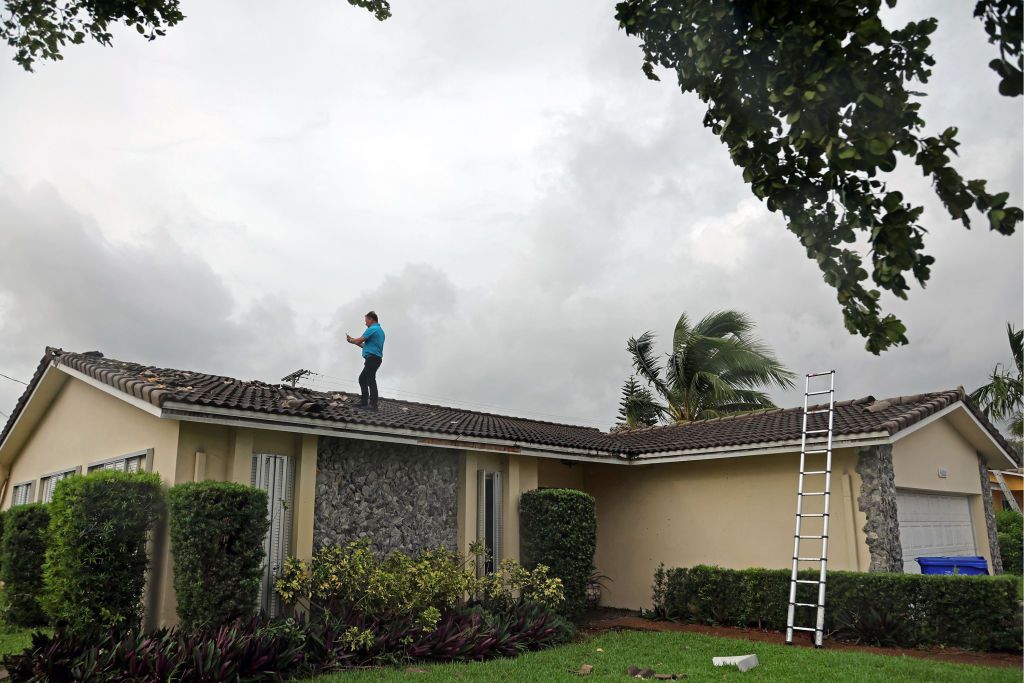 An insurance adjuster takes pictures atop a roof stripped of its tiles in Hollywood, Florida, on Sept. 28 after a reported tornado touched down overnight.