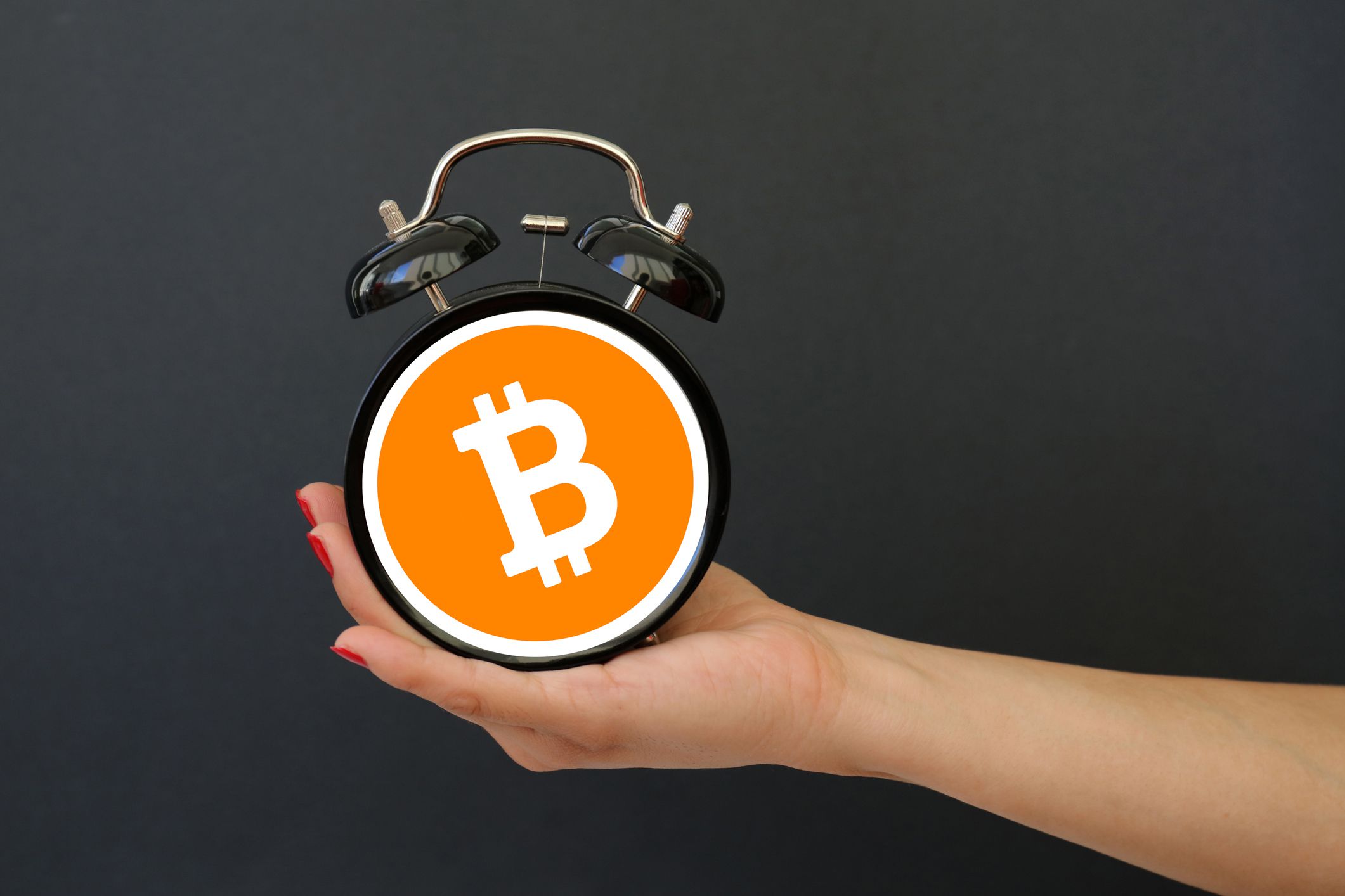 Person holds a clock with a Bitcoin symbol