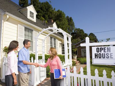 Couple shaking hands with real estate agent at open house