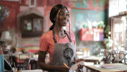 A waitress with an apron smiling.