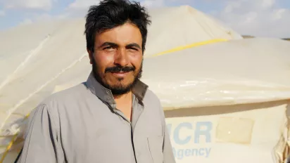 A refugee man smiling at the camera.