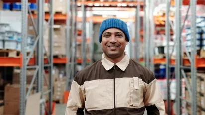 A person working in a warehouse, smiling at the camera.