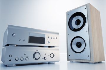 A home stereo receiver and amplifier next to a single bookshelf speaker