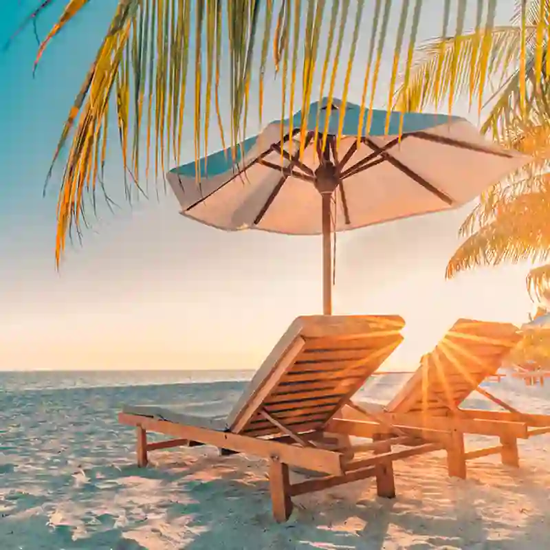 Two wooden slat reclining chairs and an umbrella on a sunny beach
