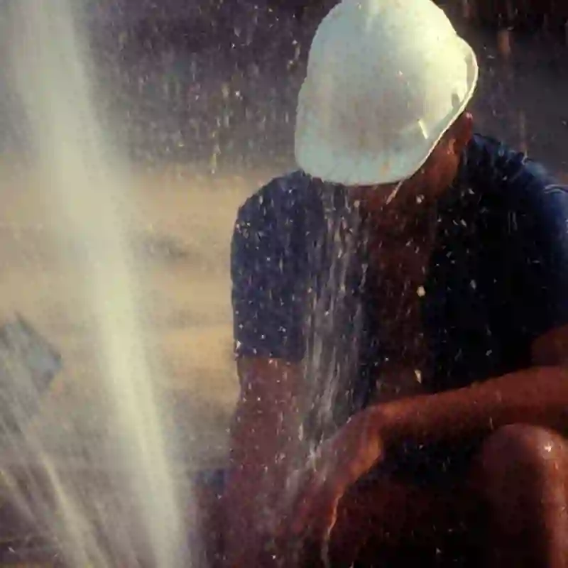 A worker fixes a gushing broken water pipe.