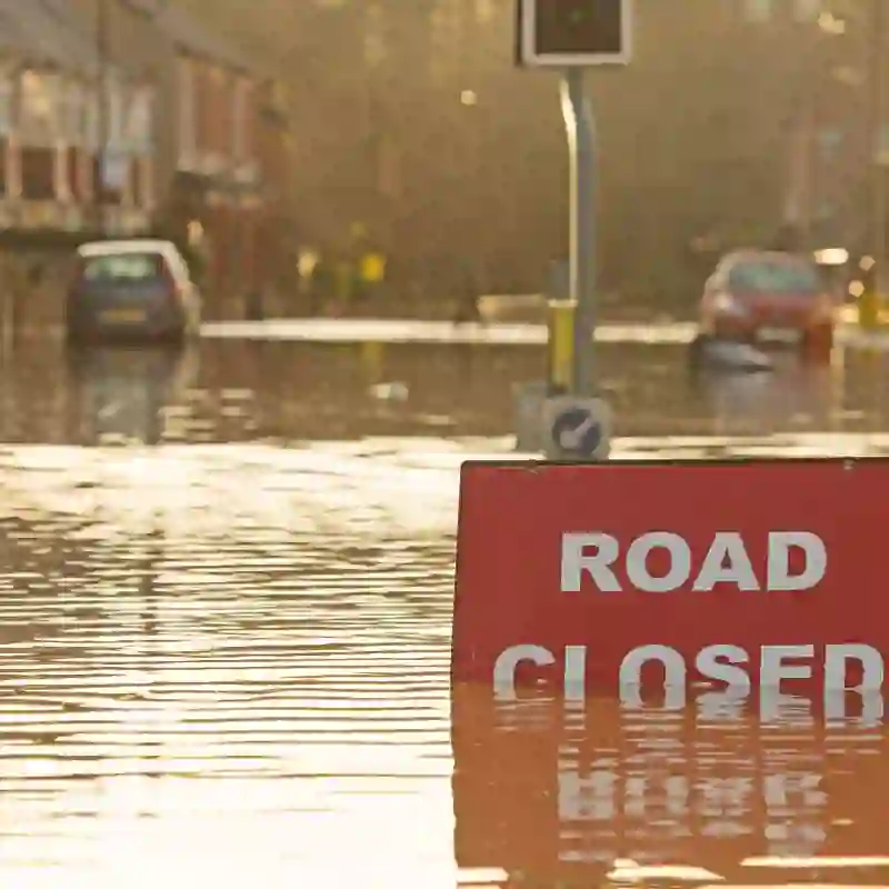 A street flooded with cars stuck and a "Road Closed" sign.