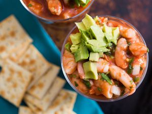 Overhead shot of poached shrimp in tomato-based sauce and diced avocado served in cocktail glass