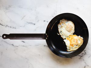 fried eggs in a carbon steel skillet on a marble countertop