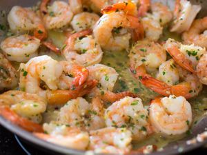 Shrimp scampi in a pan with lots of butter, garlic and parsley. 