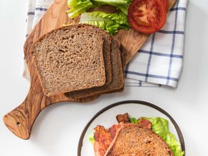 Overhead shot of sliced multigrain bread, tomato slice, and lettuce for BLT