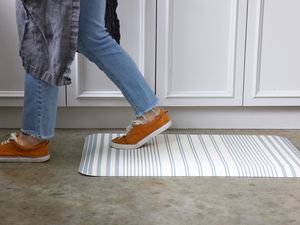 A person walking across a stripped anti-fatigue mat on a kitchen floor