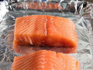 Two salmon fillets on a baking sheet that's lined with aluminum foil. 