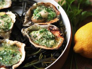 Closeup of grilled oysters topped with Parmesan basil compound butter.
