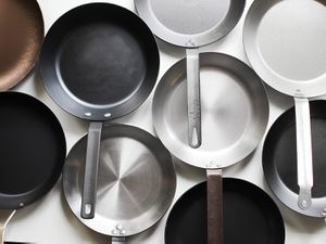 lineup of carbon steel skillets on a white surface