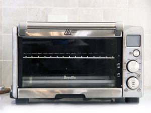 breville compact toaster oven on a white marble counter with white tile backdrop