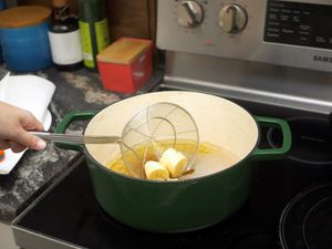 a spider strainer being used to deposit sliced plantains into hot oil