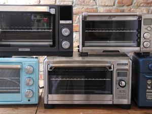 Toaster ovens stacked on top of each other in front of a brick background