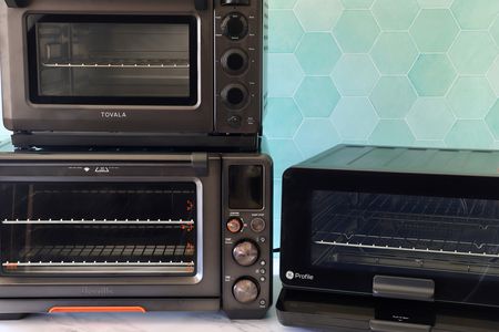 three countertop smart ovens on a marble surface with a teal green tile background