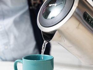 A closeup look at the Breville tea kettle pouring water into a light blue mug