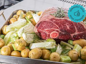 An uncooked roast surrounded by potatoes and fennel and situated in a roasting pan