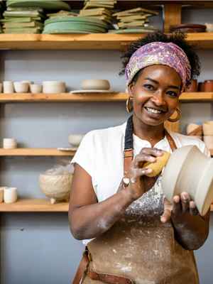 A smiling business owner making a clay pot with a tile showing shopper insights