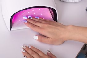 hand with manicure nails in gel polish lamp