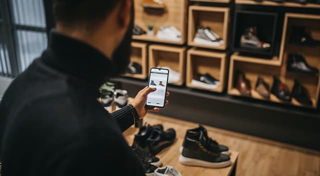 A customer seated in a shoe store checks online inventory from his smartphone.