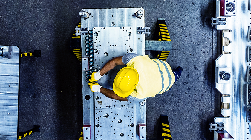 Obrero de construcción que usa un casco amarillo mientras trabaja en una maquinaria