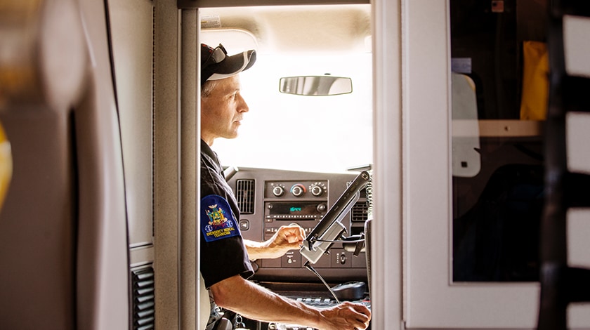 A man in a uniform sits in the front of a truck looking at a mounted monitor screen