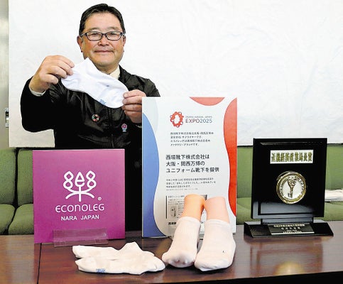 万博スタッフの公式靴下をアピールする西垣社長（奈良県庁で）