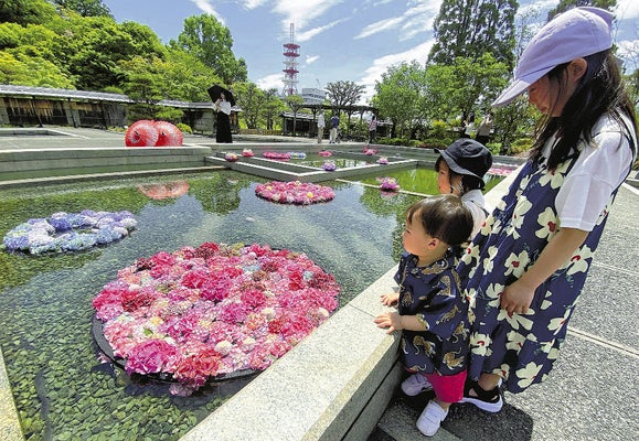 水面に浮かぶ色とりどりの花を見る子どもたち（松山市で）