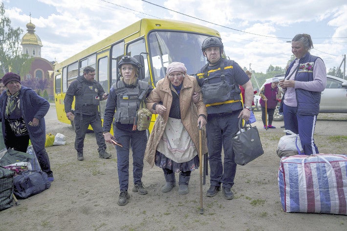 １２日、ウクライナ北東部ハルキウ州ボウチャンスクから避難し、救助隊に支えられて歩く女性＝ＡＰ