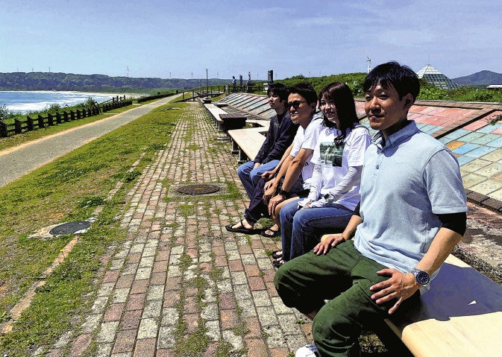 「世界一長いベンチ」に腰かける地元住民ら（１１日、石川県志賀町で）