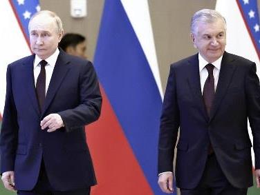 ２７日、ウズベキスタンの首都タシケントで、ミルジヨエフ大統領（右）と会談に向かうロシアのプーチン大統領＝ＡＰ