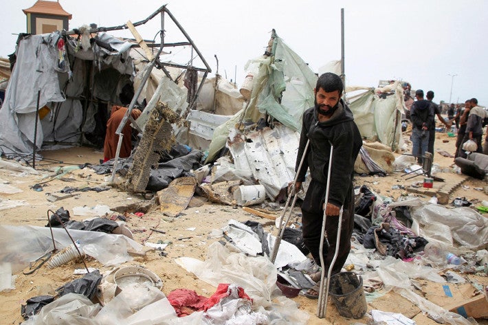 ２８日、ガザ最南部ラファで、イスラエル軍の攻撃で壊れたテントのそばを歩く男性＝ロイター