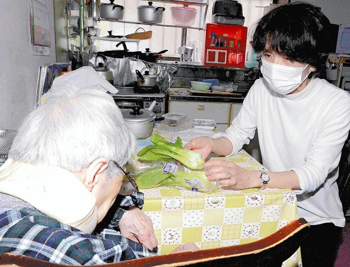 一人暮らしの女性（左）に料理の希望を尋ねるヘルパーの川合さん（埼玉県志木市で）