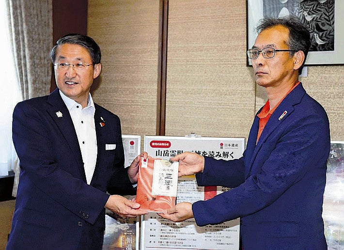 記念誌を平井知事（左）に手渡す西田教育長（県庁で）