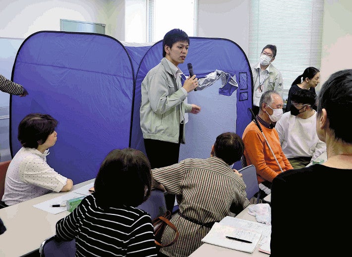 プライバシー保護のための屋内テントについて説明する市職員（香芝市で）