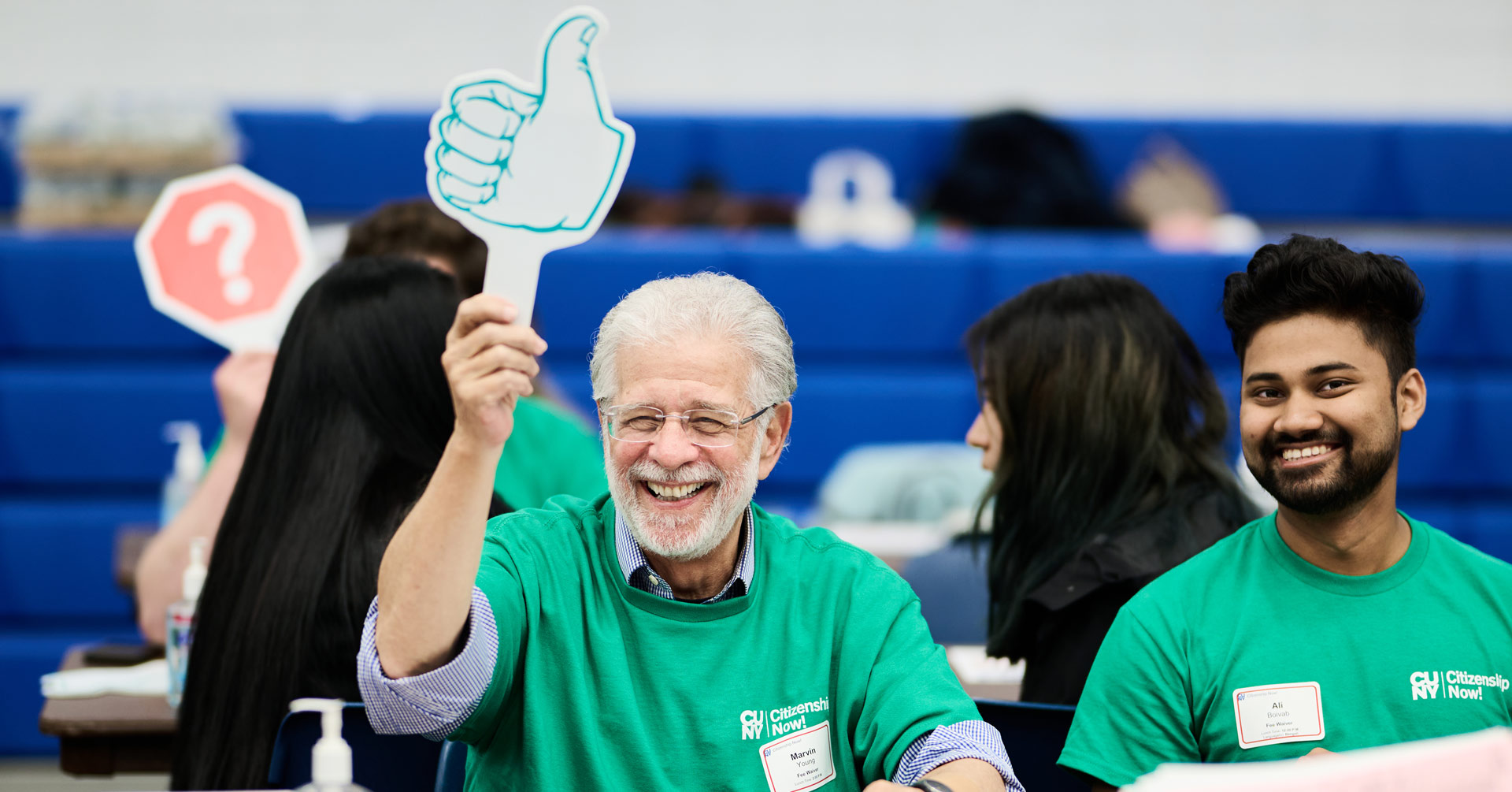 CUNY Citizenship Now! volunteer holds up a thumbs up sign to indicate that they are ready for the next attendee.