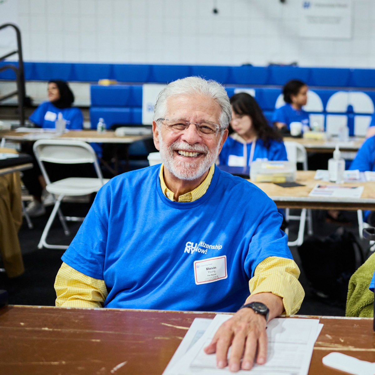 A CUNY Citizenship Now! volunteer sits at a table during the citizenship drive.