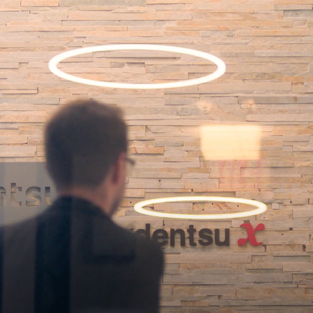 A man in front of the Dentsu logo