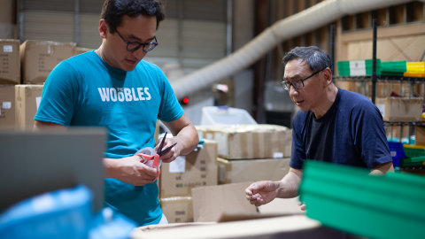 A photo of Adrian Zhang, co found of The Woobles, packaging shipping boxes.