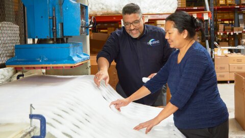 A photo of two Compac Industries employees observing material in a factory.
