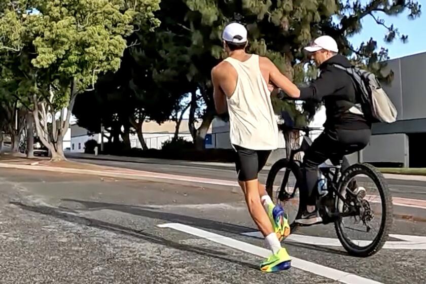 A video screenshot from a cyclist course marshal shows Esteban Prado, left, receiving a bottle of water from his father. That action resulted in Prado's disqualification from the Hoag OC Marathon. "We were forced to disqualify a participant after it was confirmed they received unauthorized assistance from an individual on a bicycle, in violation of USA Track & Field rules and our race regulations," race director Gary Kutscher said.