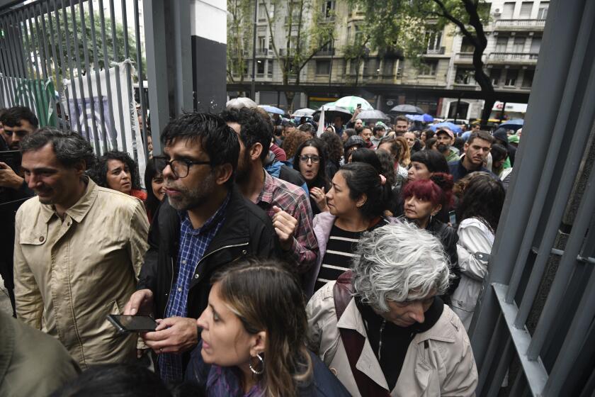 State employees enter their workplace after they were temporarily prevented from entering their workplace due to an anti-government protest in support of workers who were laid off as part of state economic downsizing measures, in Buenos Aires, Argentina, Wednesday, April 3, 2024. According to the State Workers Association, more than 11 thousand dismissals of state employees have been carried out by Javier Milei’s government. (AP Photo/Gustavo Garello)
