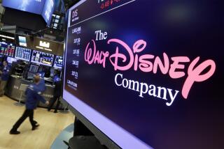 A pink-and-white logo for the Walt Disney Company appears on a screen in an office with other screens in the background.