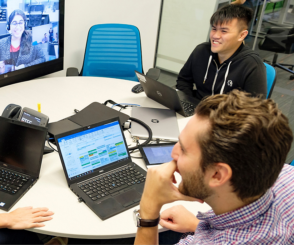 Dva muži a jedna žena, kteří se během videohovoru aktivně účastní obchodní schůzky s notebooky v moderní kanceláři